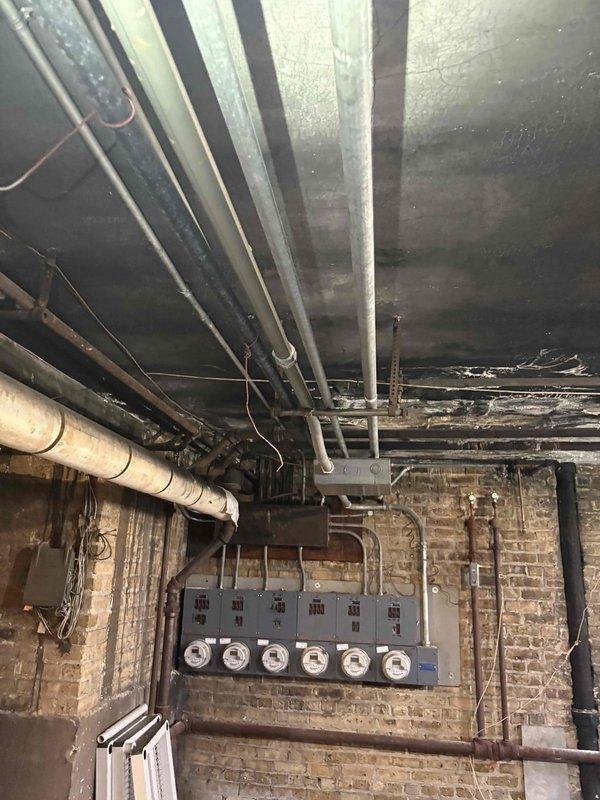 Responded to priority service call for low water pressure and lack of hot water at residential property. Previous contractor had identified rust buildup and clog in piping system but declined to perform repairs. Upon arrival, conducted thorough inspection of basement plumbing infrastructure, including exposed supply lines, distribution piping, and water heating system. Assessed condition of aging galvanized steel pipes showing visible corrosion and rust accumulation throughout the water supply network. Evaluated complex piping configuration including multiple branch lines, vertical risers, and horizontal runs servicing the property. Documented extensive rust deposits and sediment blockage restricting water flow through compromised sections of piping. Inspected electrical panel and utility connections in basement area to assess overall mechanical systems condition. Photographed affected piping sections, ceiling-mounted infrastructure, and utility room layout for documentation purposes. 