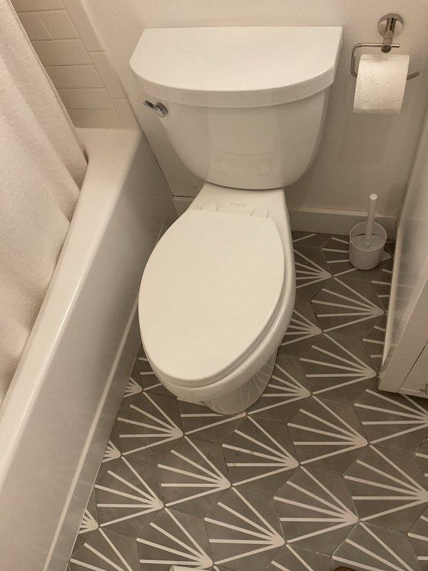 Completed commercial toilet installation in bathroom with modern tile finishes. Installed standard two-piece white porcelain toilet unit with proper measurements and positioning, ensuring compliance with fixture spacing requirements. All plumbing connections secured and tested for proper operation.