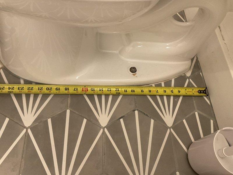 Completed commercial toilet installation in bathroom with modern tile finishes. Installed standard two-piece white porcelain toilet unit with proper measurements and positioning, ensuring compliance with fixture spacing requirements. All plumbing connections secured and tested for proper operation.