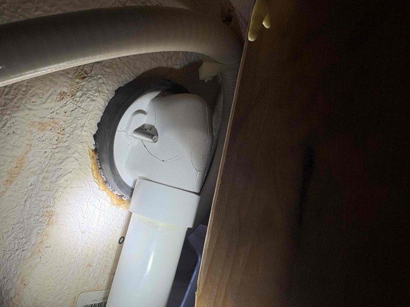 Responded to call for active water leak beneath bathtub in master bedroom. Accessed plumbing through access panel and located leak source on white PVC drain pipe running vertically in wall cavity between master bathtub and adjacent closet. Documented plumbing configuration showing P-trap assembly with black rubber coupling and standard white PVC drainage components. Photographed affected area revealing drain pipe connections, copper supply lines, and cabinet interior to verify leak location and assess extent of water damage for necessary repairs.