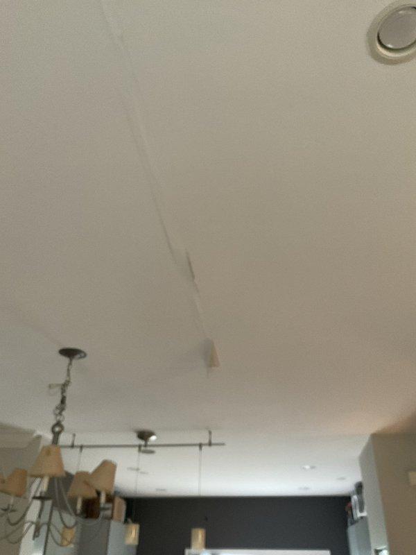 Responded to report of water leak causing damage to first floor ceiling, with customer suspecting furnace water line as source. Upon inspection, identified extensive water damage to ceiling with significant staining, discoloration, and material deterioration in multiple areas. Documented existing damage showing brown and tan water stains with irregular patterns indicating prolonged moisture infiltration from above. Examined ceiling cavity through deteriorated sections and assessed visible crack/seam running diagonally across affected area. Investigated potential source points including furnace water line connection as reported. Captured photographic documentation of damaged ceiling sections and overall affected areas for record and estimate purposes. Recommended further investigation of upper level plumbing connections and furnace humidifier line to pinpoint exact leak source before proceeding with repairs.