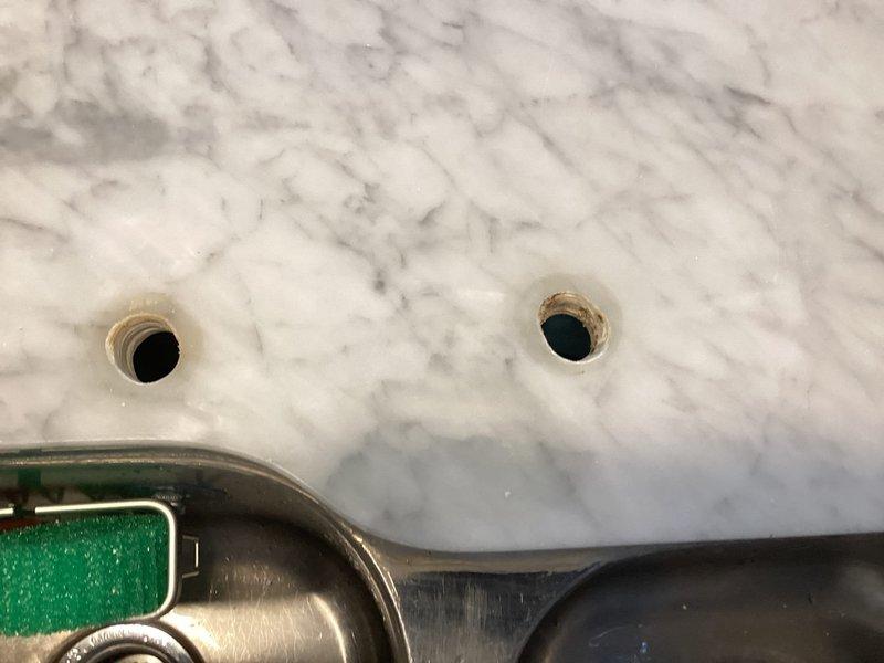 Completed installation of commercial-style pull-down kitchen faucet with pre-rinse spray head on double-basin stainless steel sink. Drilled mounting holes through marble countertop, secured faucet assembly with appropriate hardware, and connected water supply lines. Tested operation of pull-down spray mechanism and verified proper drainage in both sink basins upon completion.