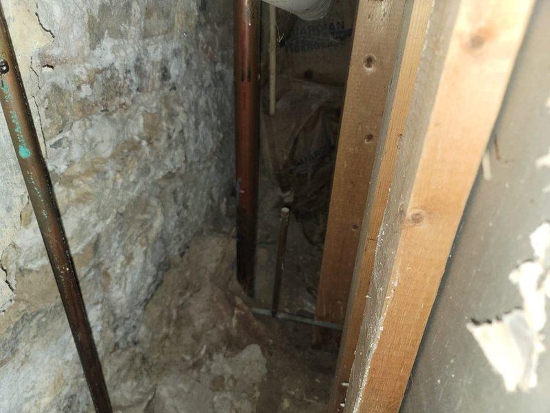 Responded to commercial water leak investigation where contaminated water was surfacing from a capped plumbing line beneath cabinetry. Upon inspection, discovered significant water infiltration issues affecting both structural elements and finished spaces. In the wall cavity area, identified severe efflorescence and mineral deposits on concrete block surfaces with visible copper piping, indicating chronic moisture problems and potential drainage system failures. In the adjacent finished space, documented extensive water damage to flooring materials along baseboards with rust-colored staining patterns consistent with contaminated water seepage from the compromised capped line. Photographed all affected areas including deteriorated concrete surfaces, damaged flooring planks, and water intrusion patterns for documentation and further remediation planning.