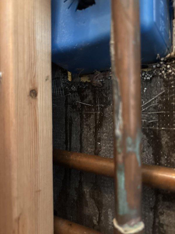 Capped off shower plumbing lines in bathroom undergoing renovation. Accessed exposed copper supply pipes within wall cavity and properly sealed termination points to prevent water flow to the shower fixture area. Work performed with wall framing exposed, allowing clear access to vertical copper piping system running through the stud cavity.