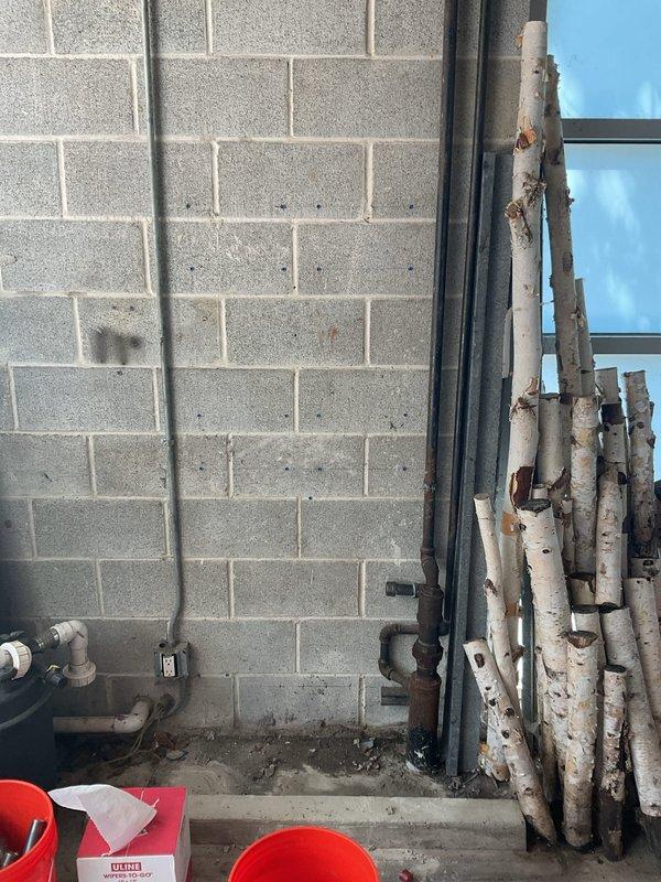 Inspected and assessed deteriorated plumbing infrastructure in basement utility area, including heavily corroded vertical pipe with significant rust oxidation and failing fittings requiring replacement. Documented existing conditions of aging plumbing system with pressure gauge assembly and PVC piping network to provide customer with visual evidence supporting recommended repair work sold during morning consultation.