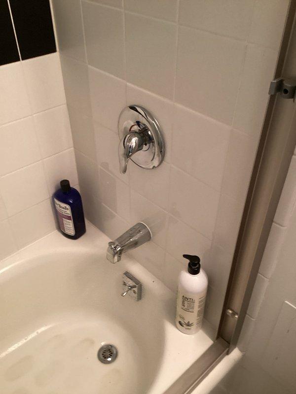 Responded to leaking tub faucet with active water flow that could not be shut off following building maintenance pipe clearing and water restoration. Upon inspection, determined debris from the water system work had compromised the faucet valve seat, preventing proper closure. Disassembled the chrome wall-mounted tub spout assembly, cleared sediment and mineral deposits from the valve mechanism, replaced worn internal components, and reassembled the fixture. Tested water flow and shutoff function to confirm proper operation with no leaks present.