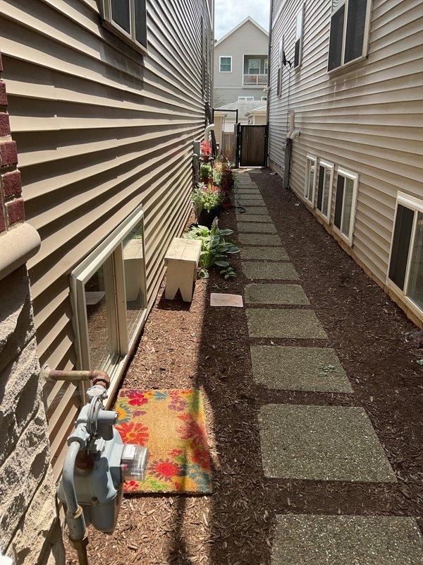 Conducted site assessment for gas line installation to serve outdoor grill in side yard location. Evaluated existing gas meter placement, determined optimal routing path through narrow passageway between structures, and assessed concrete paver walkway and landscaping considerations for trenching and pipe installation. Provided estimate for materials and labor required to run new gas piping from meter to grill connection point on rear patio area.