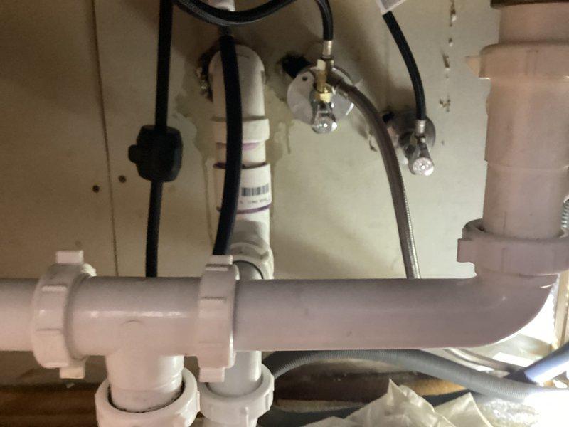 Responded to low water pressure complaint affecting kitchen and bathroom sinks in unit 2 of century-old residential property. Upon inspection, assessed existing plumbing infrastructure including undermount stainless steel kitchen sink with modern brushed stainless steel faucet and associated supply lines. Examined under-sink plumbing configuration revealing PVC drainage system with metallic braided flexible supply lines connected to faucet assembly. Evaluated water flow at both affected fixtures to determine pressure loss patterns and potential causes related to aging galvanized piping common in older homes, mineral buildup in aerators or supply lines, or partially closed shut-off valves. Documented existing conditions through photographic evidence showing current fixture installation, countertop mounting, and under-sink plumbing arrangement including supply hoses, drain connections, and shut-off valve accessibility. Investigated potential restriction points in water delivery system an