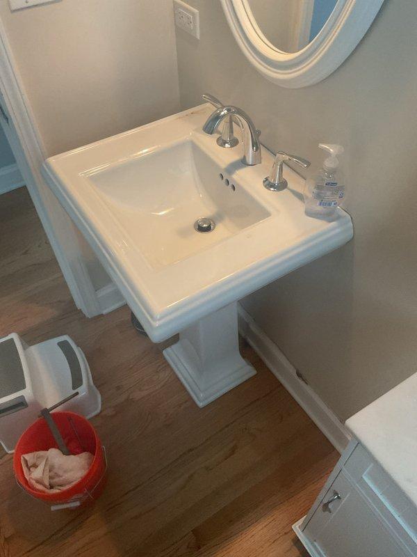 Installed new three-piece chrome faucet assembly on white pedestal sink, including central arched spout and dual lever handles for hot and cold water control. Verified proper water flow, tested drain pop-up assembly operation, and confirmed no leaks at all connection points.