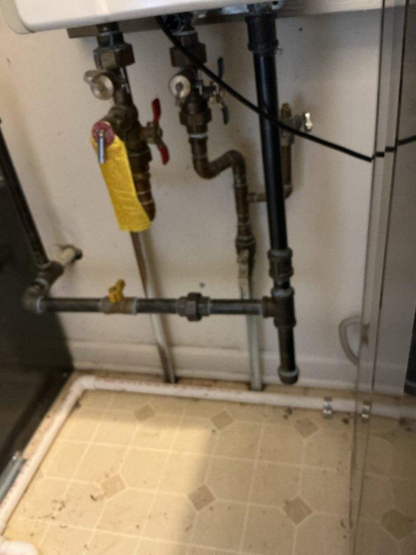 Responded to gas leak reported near water heater and furnace area. Upon arrival, conducted comprehensive visual inspection of gas piping system in mechanical room and exterior gas meter assembly. Located active leak at corroded gas piping connections near water heater installation. Performed pressure test on gas system to verify leak location and assess system integrity. Documented heavily corroded exterior gas meter piping and deteriorated connections showing significant rust accumulation and compromised fittings. Identified multiple shut-off valves with operational concerns due to age and corrosion. Photographed interior gas piping configuration including black iron pipes, brass fittings, and safety valves for documentation purposes. Exterior gas supply assembly showed extensive weathering with compromised pipe coating and joint integrity requiring immediate attention to prevent further gas escape and ensure safe operation of gas-fired appliances.