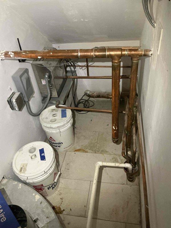 Conducted plumbing estimate for bathroom remodel project involving assessment of existing copper piping manifold system in utility area. Evaluated current plumbing infrastructure including horizontal and vertical pipe runs, joints, fittings, and connections to determine scope of work required for bathroom renovation. Documented existing conditions of copper supply lines showing various stages of oxidation and patina, noting configuration of plumbing distribution system for planning purposes. Photographed mechanical room layout and bathroom space to provide comprehensive visual reference for proposed piping modifications and fixture installations.