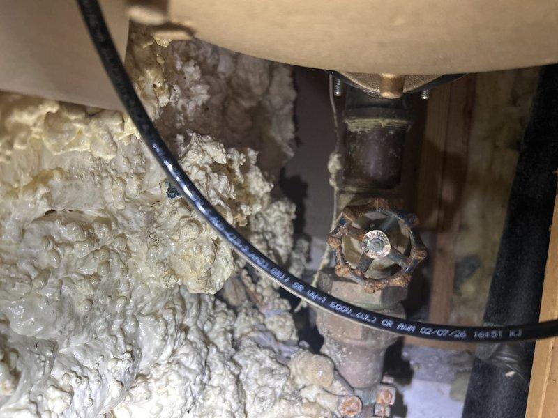 Completed piping installation work involving securing and stabilizing plumbing lines. Strapped and tightened copper pipes with brass fittings to ensure proper support and eliminate movement. Installed white plastic plumbing fixture with valve assembly on baseboard area, including brass-colored adjustment valve with threaded components. Performed comprehensive pressure testing of all connections to verify system integrity and identify any potential leaks. All piping secured to code specifications with appropriate strapping, and pressure test confirmed system is operating within normal parameters with no leaks detected.