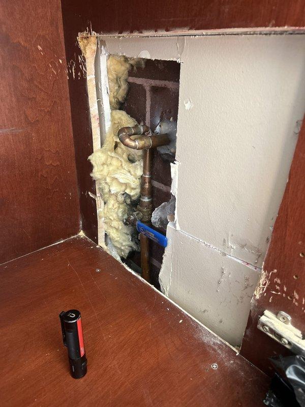Responded to warranty callback for leaking exterior spigot previously installed. Upon arrival, accessed interior wall cavity to inspect installation and identify source of leak. Removed wall panel section to expose copper supply lines, shutoff valves, and connection points. Inspection revealed improper seal or fitting issue at spigot connection causing water infiltration. Tightened compression fittings, verified proper valve operation, and tested system under pressure to confirm leak was resolved. Reinstalled wall access panel and restored work area to original condition.