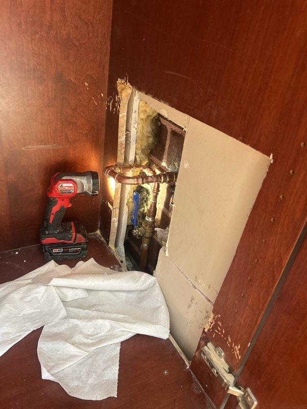 Responded to warranty callback for leaking exterior spigot previously installed. Upon arrival, accessed interior wall cavity to inspect installation and identify source of leak. Removed wall panel section to expose copper supply lines, shutoff valves, and connection points. Inspection revealed improper seal or fitting issue at spigot connection causing water infiltration. Tightened compression fittings, verified proper valve operation, and tested system under pressure to confirm leak was resolved. Reinstalled wall access panel and restored work area to original condition.