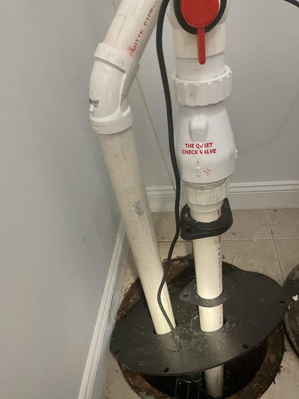 Installed new ejector pump system with check valve assembly in basement utility area. The pump was found to be running continuously upon installation, indicating a potential issue with the float switch mechanism or check valve operation that will require adjustment or troubleshooting to ensure proper cycling.