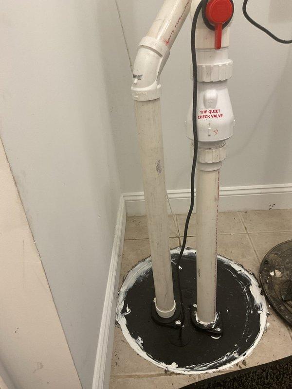 Installed new ejector pump system with check valve assembly in basement utility area. The pump was found to be running continuously upon installation, indicating a potential issue with the float switch mechanism or check valve operation that will require adjustment or troubleshooting to ensure proper cycling.