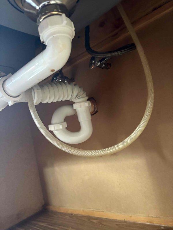 Completed priority water treatment system installation at residential property. Installed under-sink water filtration unit beneath kitchen double-basin sink, connecting system to existing cold water supply line with braided flexible hose and integrating discharge line into existing PVC drain assembly. Verified all connections for proper seal, tested system operation, and confirmed no leaks at supply lines, filter housing, or drain connections.