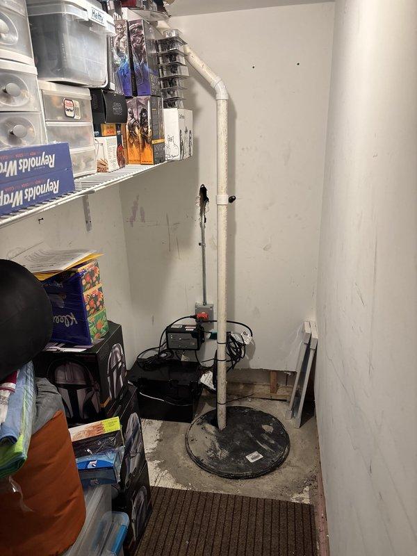 Installed new black submersible sump pump in utility storage room with proper discharge piping and float switch assembly. Unit was mounted on circular base plate with vertical discharge pipe routed along wall, ensuring proper operation and drainage capability for basement water management.