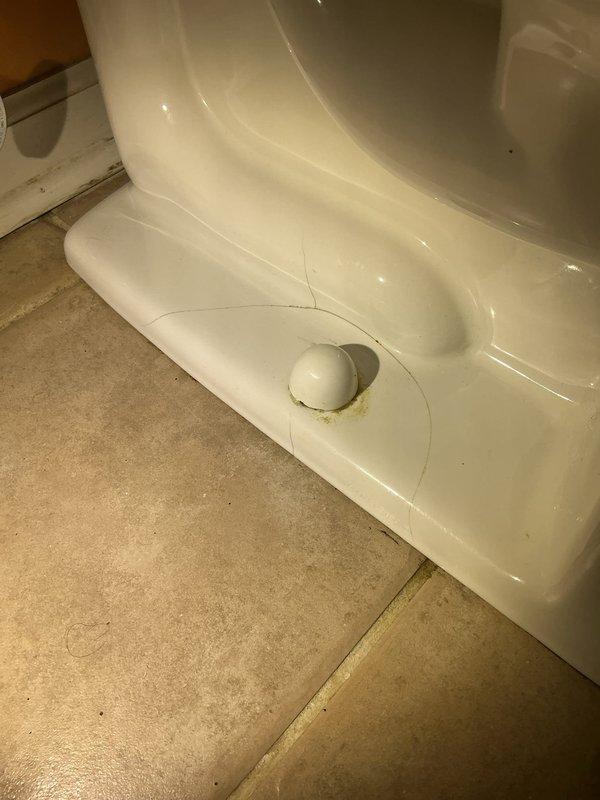 Responded to a plumbing service call for a cracked toilet base. Upon inspection, identified a structural crack in the porcelain at the toilet pedestal that compromised the fixture's integrity. Documented the damage with photographs showing the crack pattern and condition of the floor mounting hardware for repair estimate and replacement recommendations.