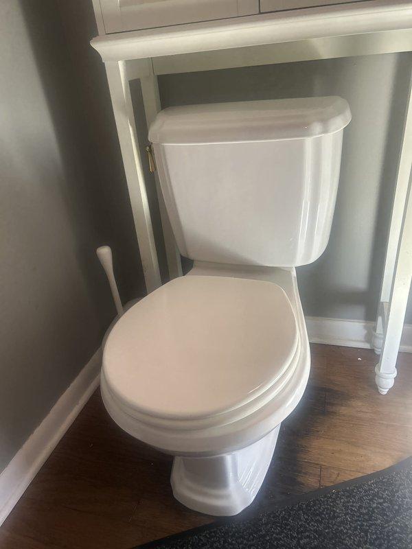 Responded to service call for toilet leaking at base. Upon arrival, confirmed active water leak at toilet base with significant water damage to surrounding hardwood flooring and mineral deposit buildup around floor flange. Inspected toilet installation and identified failed wax ring seal as source of leak. Documented existing conditions including water staining on floor and mineral accumulation. Coordinated with tenant to confirm arrival time prior to service.