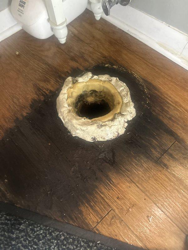 Responded to service call for toilet leaking at base. Upon arrival, confirmed active water leak at toilet base with significant water damage to surrounding hardwood flooring and mineral deposit buildup around floor flange. Inspected toilet installation and identified failed wax ring seal as source of leak. Documented existing conditions including water staining on floor and mineral accumulation. Coordinated with tenant to confirm arrival time prior to service.