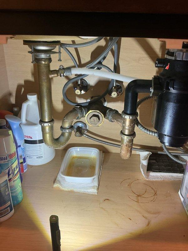Responded to priority service call for water damage investigation with visible ceiling staining below kitchen plumbing. Upon inspection, identified active leak from kitchen sink drain assembly and P-trap connections causing water intrusion to ceiling below. Tightened all trap connections, replaced deteriorated tailpiece gasket, and verified garbage disposal drain connections for proper seal. Tested all fixtures under full water flow to confirm leak resolution and advised monitoring ceiling stain for drying over next several days.