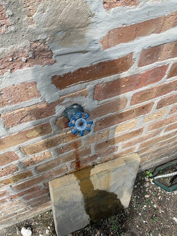 Replaced deteriorated exterior hose bib and mounting block on brick wall. The original water spigot showed significant weathering and the mounting surface had deteriorated, requiring removal and installation of new fixture with proper sealing to prevent water intrusion into the wall structure.