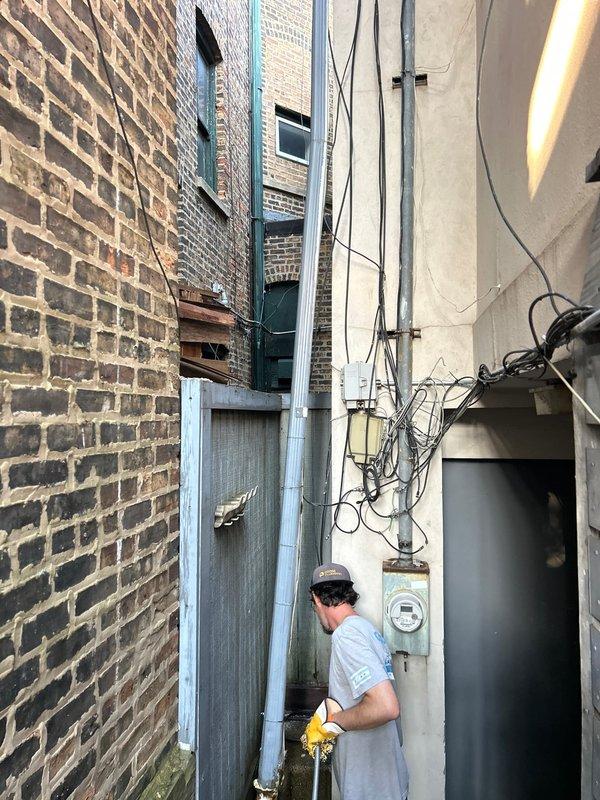 Responded to a sewer line backup affecting a century-old residence. Accessed the main sewer line through the narrow exterior alleyway between buildings, navigating confined workspace with overhead utilities and electrical infrastructure. Successfully cleared the blockage and restored proper drainage to the system.