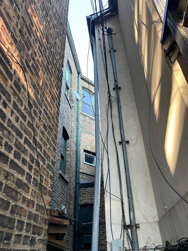 Responded to a sewer line backup affecting a century-old residence. Accessed the main sewer line through the narrow exterior alleyway between buildings, navigating confined workspace with overhead utilities and electrical infrastructure. Successfully cleared the blockage and restored proper drainage to the system.