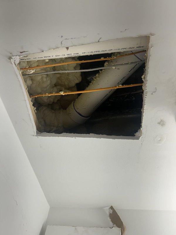 Responded to water leak reported in basement closet ceiling with water accumulation in light fixture. Upon arrival, inspected mechanical room housing heating/boiler system with associated piping network. Cut access opening in ceiling to investigate source of leak. Inspection revealed gray PVC piping running through ceiling joists with evidence of moisture damage and staining on surrounding surfaces. Traced leak to compromised plumbing connection in vicinity of mechanical equipment. Documented conditions with photographs showing mechanical system, pressure gauge, valve assemblies, and ceiling cavity access point. Identified leak source and provided assessment for necessary repairs to prevent further water intrusion and damage to electrical fixtures below.