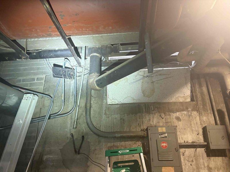 Conducted comprehensive site assessment of commercial sump pump system requiring replacement of both primary and secondary pumping mechanisms within existing basin. Evaluated current installation including discharge piping, electrical connections, and basin configuration in basement utility area with concrete block construction. Documented existing conditions through photographic survey showing vertical discharge pipe routing, utility panel locations, and overhead infrastructure to develop accurate replacement estimate for dual pump system upgrade.