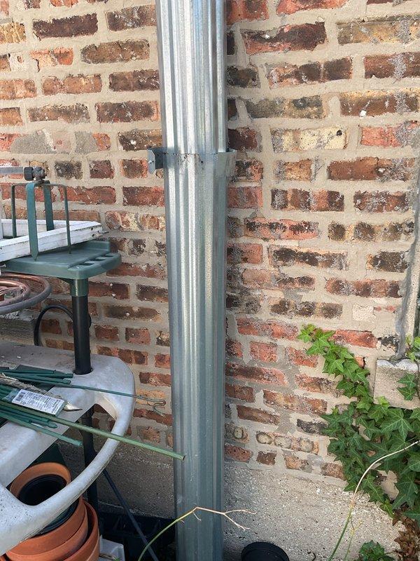 Responded to commercial clogged drain service call at outdoor patio area. Upon arrival, located and inspected exterior drainage system including vertical downspout and floor drain assembly positioned against brick wall near gardening storage area. Successfully cleared obstruction from drain line and verified proper water flow through the system.