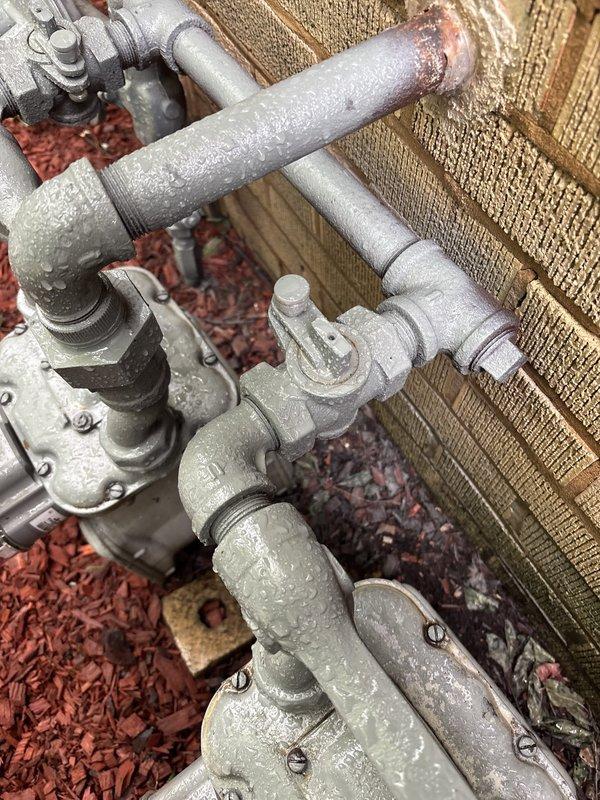 Responded to service call for multiple gas leak concerns at property, including leak at water heater connection point and two additional gas leak locations. Upon arrival, conducted thorough visual inspection of exterior gas piping system mounted against foundation wall. Identified deteriorated pipe connections with visible corrosion and worn protective coating on threaded fittings near water heater installation point. Performed comprehensive pressure test on gas line system to verify integrity and locate all leak sources. Inspected exterior gas meter assembly and associated shutoff valves positioned in landscaped area with visible weathering on pipe surfaces. Documented existing conditions of aged piping infrastructure showing signs of paint deterioration and potential compromise points at wall penetrations. All identified leak locations were assessed and documented photographically for repair recommendations.
