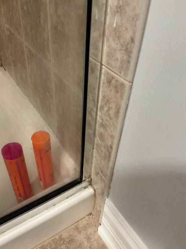 Responded to reassess water leak with ceiling already opened for access. Upon inspection of the bathroom shower area, examined the shower enclosure, tiled walls, glass door assembly, and surrounding fixtures for signs of moisture intrusion or active leaking. Documented conditions with photographs showing the beige marble-effect tiled shower walls, white shower pan with center drain, chrome-framed glass door assembly, and bathroom floor area. No active water leakage was observed at the time of inspection, and all visible plumbing fixtures, shower components, and tile surfaces appeared to be in good condition with proper drainage function.