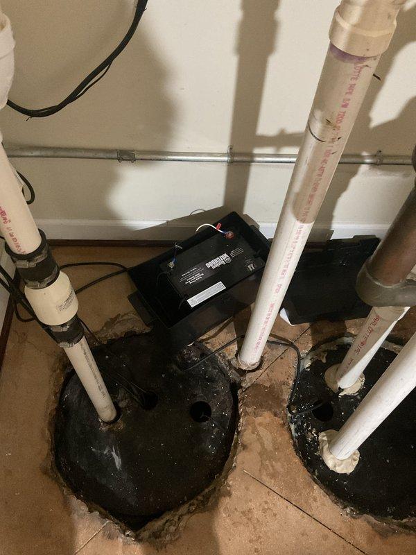 Responded to service call for non-functional sump pump with battery backup system in 24-year-old residential property. Upon arrival, conducted comprehensive diagnostic assessment of the existing sump pump installation, including primary pump unit, battery backup system, and associated discharge piping configuration.

Inspection revealed the sump pump system installed in basement utility area with PVC discharge lines and black primary pump unit mounted on basin. Evaluated electrical connections, battery backup controller mounted on wall, and integration with HVAC condensate drainage system. Testing confirmed pump failure and battery backup malfunction requiring immediate attention to prevent potential basement flooding.

Performed necessary repairs and system restoration to return sump pump and battery backup to full operational status. Verified proper pump cycling, float switch operation, and battery backup engagement during simulated power loss conditions. Tested discharge line flow a