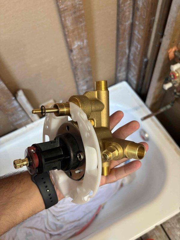 Replaced bathtub valve assembly including brass valve body, cartridge mechanism with mounting escutcheon, and control stem during bathroom renovation. Installed new water supply connections at wall penetrations in preparation for fixture completion.