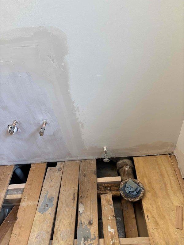 Replaced bathtub valve assembly including brass valve body, cartridge mechanism with mounting escutcheon, and control stem during bathroom renovation. Installed new water supply connections at wall penetrations in preparation for fixture completion.
