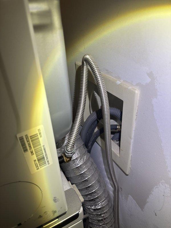 Responded to report of water leakage from washing machine drain pipe causing ceiling stains in room below. Upon inspection, identified active leak at washing machine drain connection point. Assessed water damage to ceiling drywall, noting discoloration and staining around recessed light fixture indicating ongoing moisture intrusion. Examined flexible drain hose connections and wall discharge pipe, finding improper seal at connection point allowing water to escape during drain cycles. Repaired connection by securing drain hose properly to wall discharge pipe with appropriate clamp, ensuring watertight seal. Verified repair by running test cycle and confirming no further leakage at connection point. Advised monitoring ceiling stains for any progression and recommended professional drywall repair once area fully dries to address cosmetic damage.