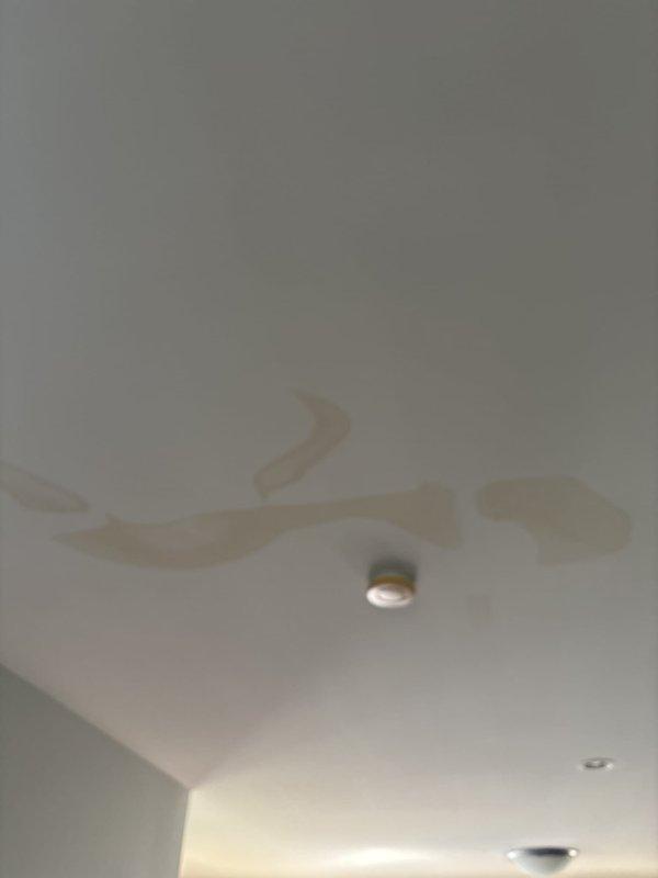 Responded to report of water leakage from washing machine drain pipe causing ceiling stains in room below. Upon inspection, identified active leak at washing machine drain connection point. Assessed water damage to ceiling drywall, noting discoloration and staining around recessed light fixture indicating ongoing moisture intrusion. Examined flexible drain hose connections and wall discharge pipe, finding improper seal at connection point allowing water to escape during drain cycles. Repaired connection by securing drain hose properly to wall discharge pipe with appropriate clamp, ensuring watertight seal. Verified repair by running test cycle and confirming no further leakage at connection point. Advised monitoring ceiling stains for any progression and recommended professional drywall repair once area fully dries to address cosmetic damage.