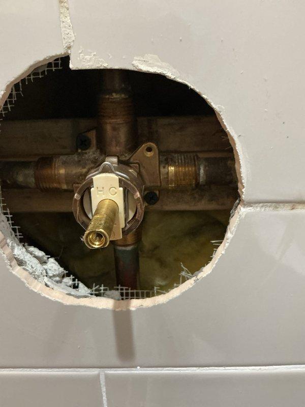 Responded to master bathroom tub/shower experiencing loud humming and vibrating noise when water temperature was adjusted to warmer settings during tub spout operation. Diagnosed faulty tub/shower mixing valve cartridge causing pressure imbalance and resonant vibration through the water supply lines. Opened wall access to expose valve assembly, removed deteriorated mixing valve cartridge with worn pressure-balancing components, and installed new replacement cartridge. Tested system operation across full temperature range to verify elimination of humming noise and proper pressure balancing between hot and cold water supplies.
