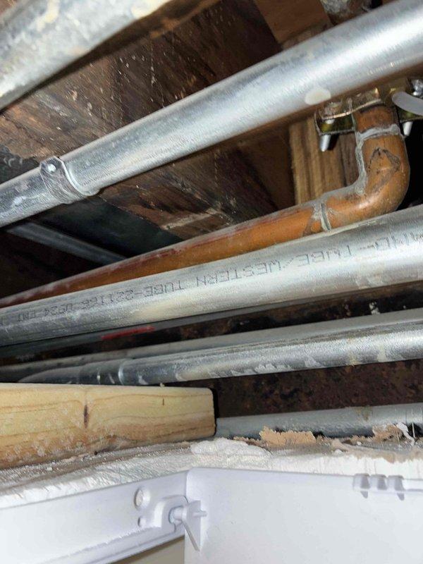 Responded to priority water leak service call and accessed exposed plumbing infrastructure in ceiling area to identify source of leak. Located compromised pipe connection at copper elbow joint fitting among horizontal supply lines running between ceiling joists. Inspected affected piping, secured leaking connection, and verified proper operation of surrounding plumbing system to ensure no additional compromised fittings were present.