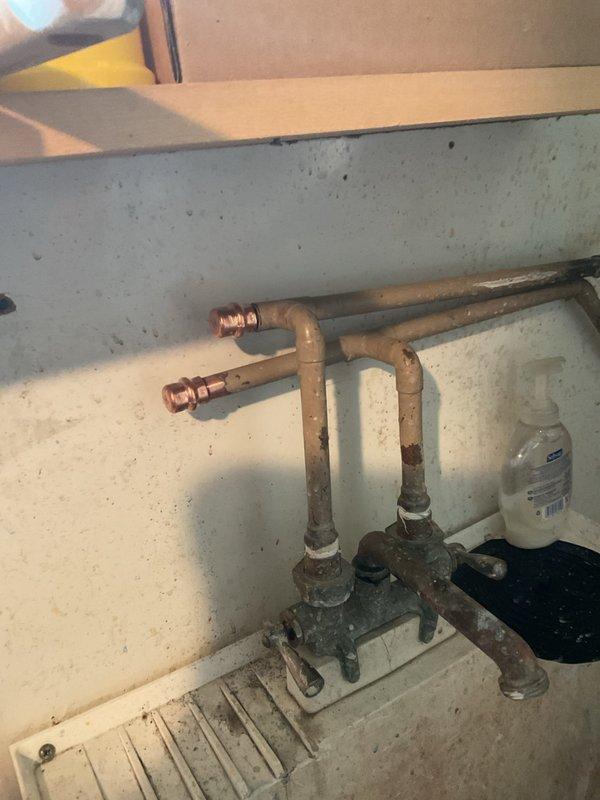 Responded to emergency call for leaking hot water valve in basement of century-old home. Upon arrival, found that homeowner's attempt to tighten valve had exacerbated the leak. Located and identified the appropriate shut-off valve for the affected line, which had been previously unknown to the homeowner. Assessed copper piping system showing significant age-related oxidation and corrosion on valve bodies and fittings. Shut off water supply to the leaking valve and replaced failed valve assembly with new hardware. Inspected surrounding plumbing infrastructure for additional wear or potential failure points common in older installations. Tested repaired connection for leaks, restored water supply, and verified proper operation. Documented existing conditions of aged copper piping system with photographic evidence for maintenance records.