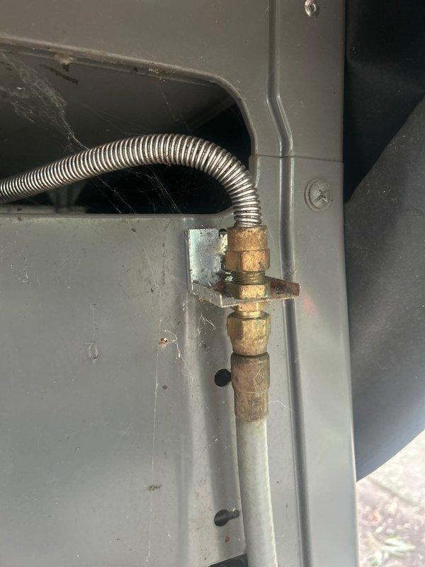 Completed assessment of exterior gas line serving outdoor grill. Found damaged flexible gas hose with evidence of animal chewing, creating potential safety hazard. Inspected existing gas line assembly including brass fittings, shut-off valve with yellow handle, and connection points. Documented corroded metal piping sections and transition to plastic piping at concrete pad location. Provided estimate for replacement of damaged gas line components to restore safe operation of outdoor grill connection.