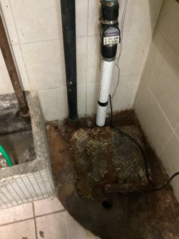 Conducted commercial plumbing assessment for ejector pump and toilet installation in facility with existing moisture damage. Evaluated bathroom area with deteriorated flooring and water-damaged surfaces indicating need for waste pump system. Documented existing toilet fixture and compromised utility room conditions with visible water intrusion patterns on concrete flooring. Provided estimate for ejector pump installation to address drainage requirements and complete toilet installation in area with inadequate gravity drainage capability.
