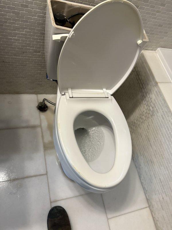 Responded to service call for toilet inspection due to suspected leak and ring formation around base. Upon arrival, performed thorough visual assessment of toilet and surrounding floor area. Identified significant discoloration and staining on grout lines and tile surfaces adjacent to toilet base, indicating potential water seepage. Inspected toilet bowl, base connection, and wax ring seal for signs of active leaking. Documented conditions with photographs showing brownish-yellow staining patterns on floor tiles near toilet fixture, consistent with chronic moisture exposure. Toilet appears structurally sound with no visible cracks in porcelain. Recommended wax ring replacement and base re-sealing to prevent further water damage to flooring and subfloor.
