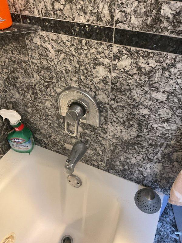 Responded to service call for hot water faucet running and leaking in shower. Upon inspection of the bathtub and shower area with decorative granite-patterned tile surround, assessed the chrome single-handle tub faucet assembly for malfunction. Completed warranty installation work on the bathtub faucet system to resolve the continuous hot water flow and leak issue, restoring proper operation of the fixture.
