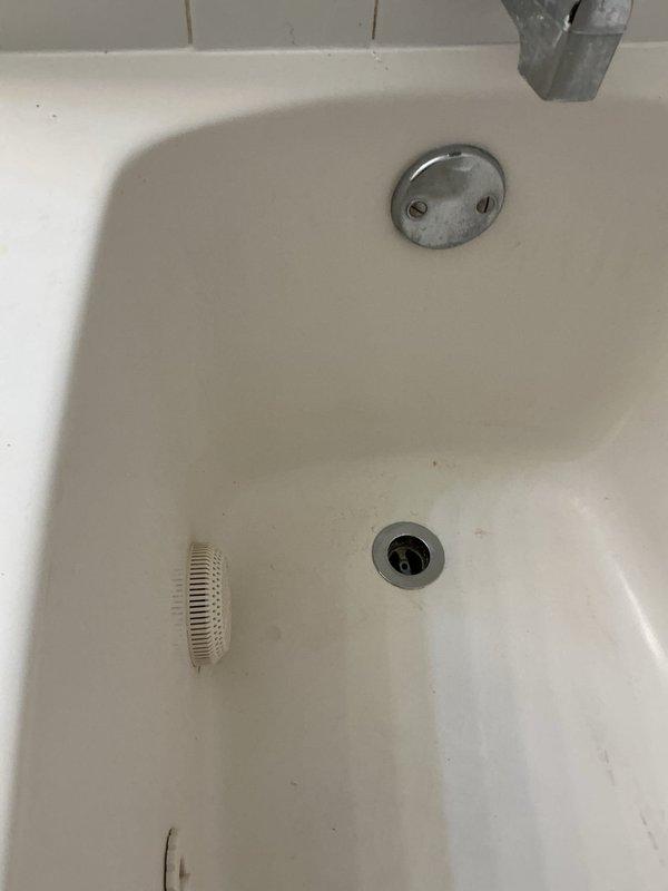 Completed replacement of two bathtub drains and one toilet using customer-supplied fixtures. The existing toilet flange showed significant rust corrosion and deterioration, with surrounding floor tiles displaying water damage staining. Both bathtub drain assemblies, including chrome drain covers and overflow plates, were successfully removed and replaced with new hardware provided by the customer.