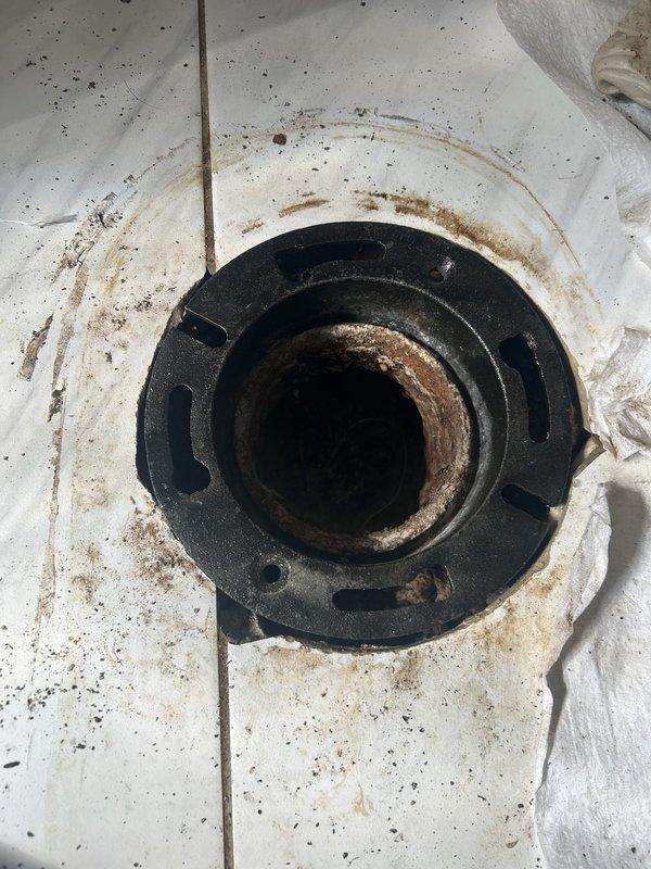# Plumbing Install - Toilet/Urinal

Completed installation of toilet flange assembly on existing plumbing system. Removed deteriorated mounting components showing significant rust and corrosion around the drain opening. Cleaned and prepared the subfloor surface, removing accumulated debris and addressing moisture damage evident around the flange area. Installed new toilet flange with proper sealing to prevent future water infiltration and ensure secure mounting for the fixture.