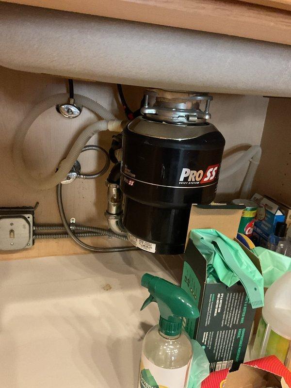 Reconfigured kitchen sink drainage system to separate garbage disposal and sink trap from shared dishwasher connection. Installed new PRO SS garbage disposal unit with independent drain line and proper mounting hardware, ensuring code-compliant plumbing configuration with dedicated trap assemblies for each fixture.