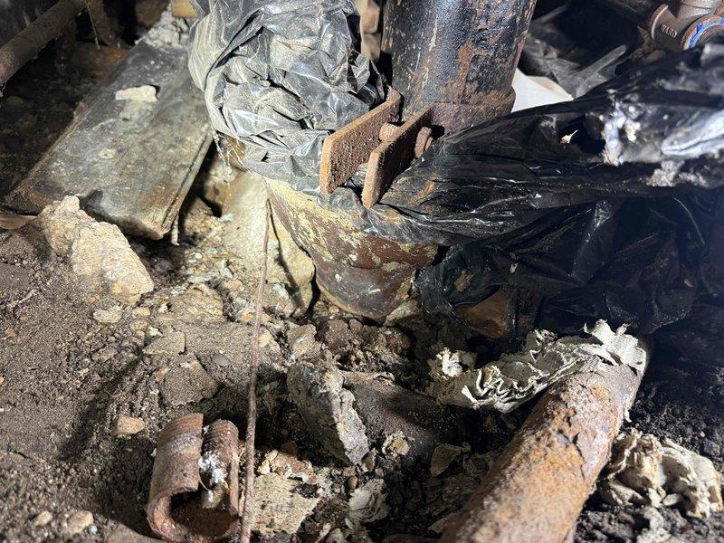 Responded to a plumbing emergency involving severely deteriorated piping and extensive corrosion damage in a crawl space or basement area. Upon inspection, discovered a vertical supply pipe with advanced rust penetration, compromised structural integrity, and failed connections at multiple welded joints. The surrounding area exhibited significant water damage, with deteriorated insulation materials, charred plastic vapor barriers, and accumulated mineral deposits indicating long-term moisture intrusion.

Removed and replaced the corroded vertical pipe section along with damaged fittings and connectors at the base. Cleared away degraded insulation foam, torn plastic sheeting, and corroded metal fragments from the work area. Addressed the compromised plumbing connections that had allowed moisture accumulation and subsequent material deterioration. Installed new piping with proper corrosion-resistant fittings to restore system functionality and prevent future water damage. Documented the 
